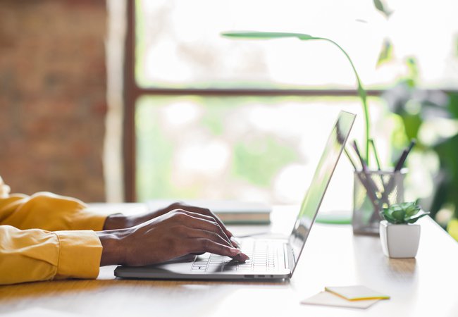 Profile photo of girl hands typing on laptop table wear yellow shirt at home